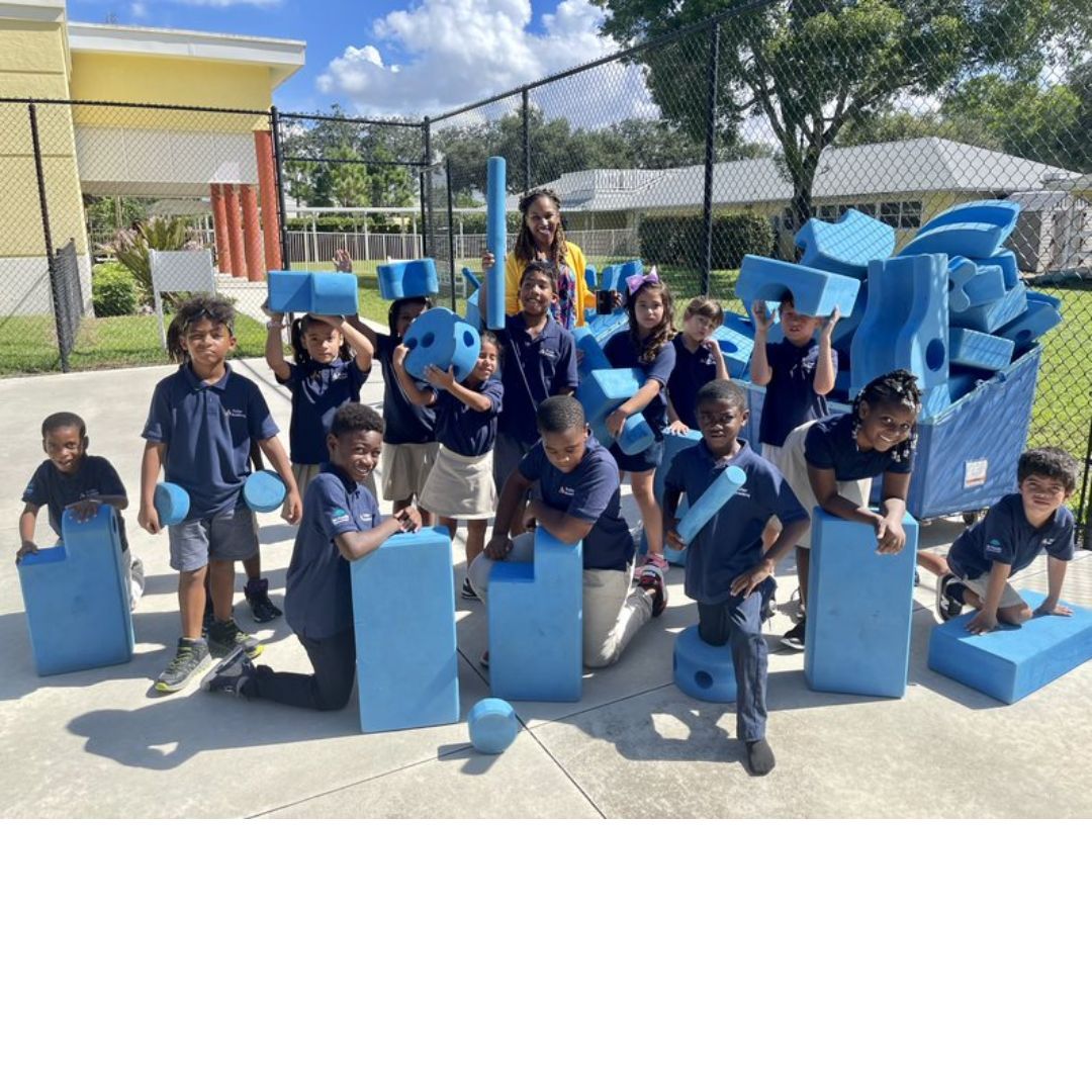 A group of children are posing for a picture with blue blocks