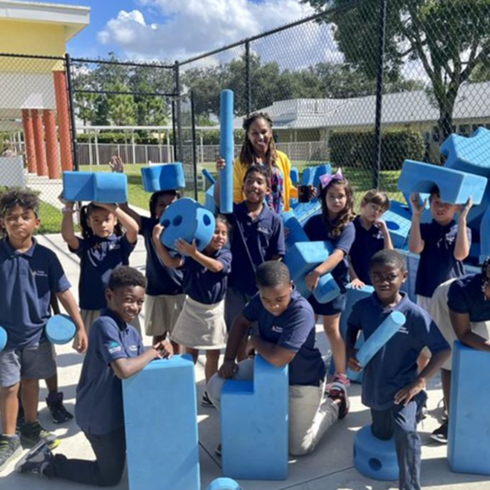 A group of children are posing for a picture with blue blocks