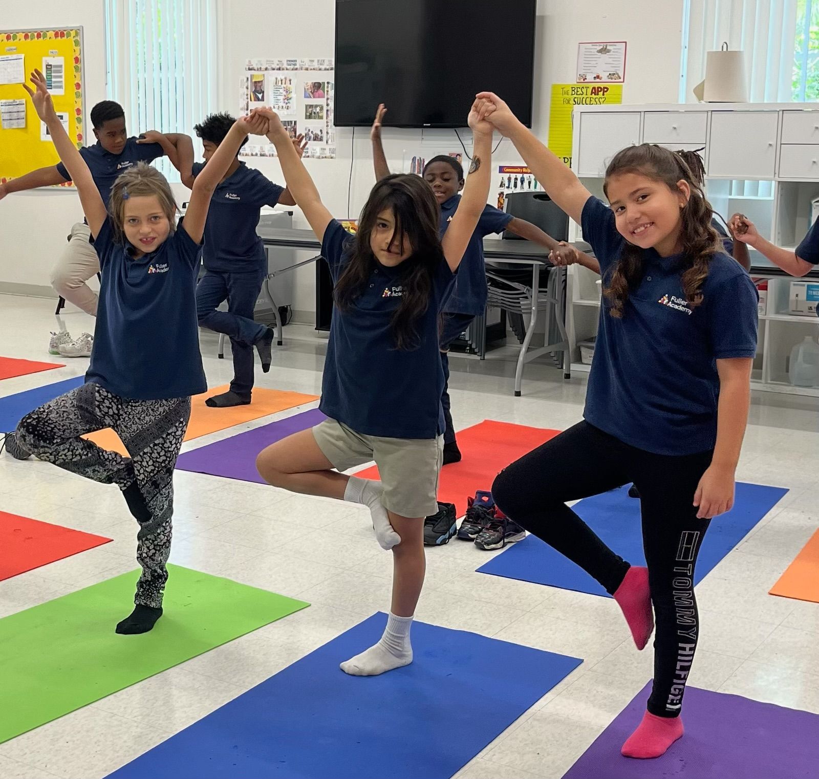 A group of young girls are practicing yoga in a classroom