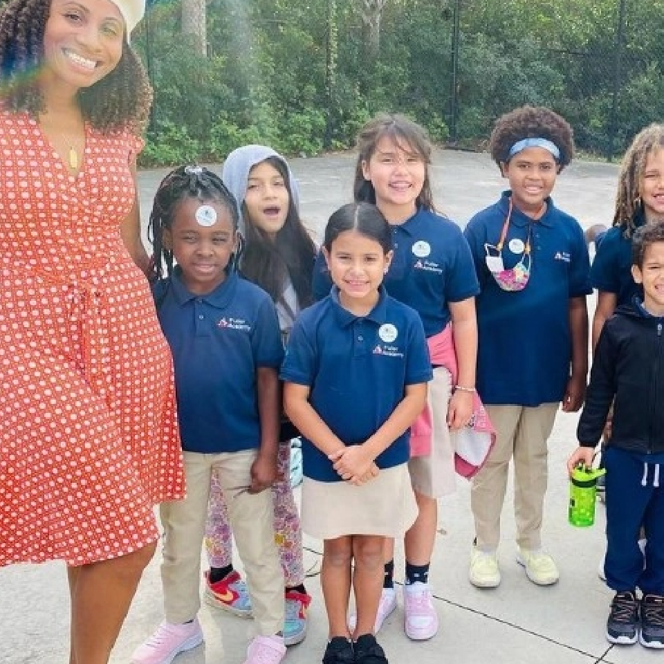 A group of children are posing for a picture with a woman in a red dress