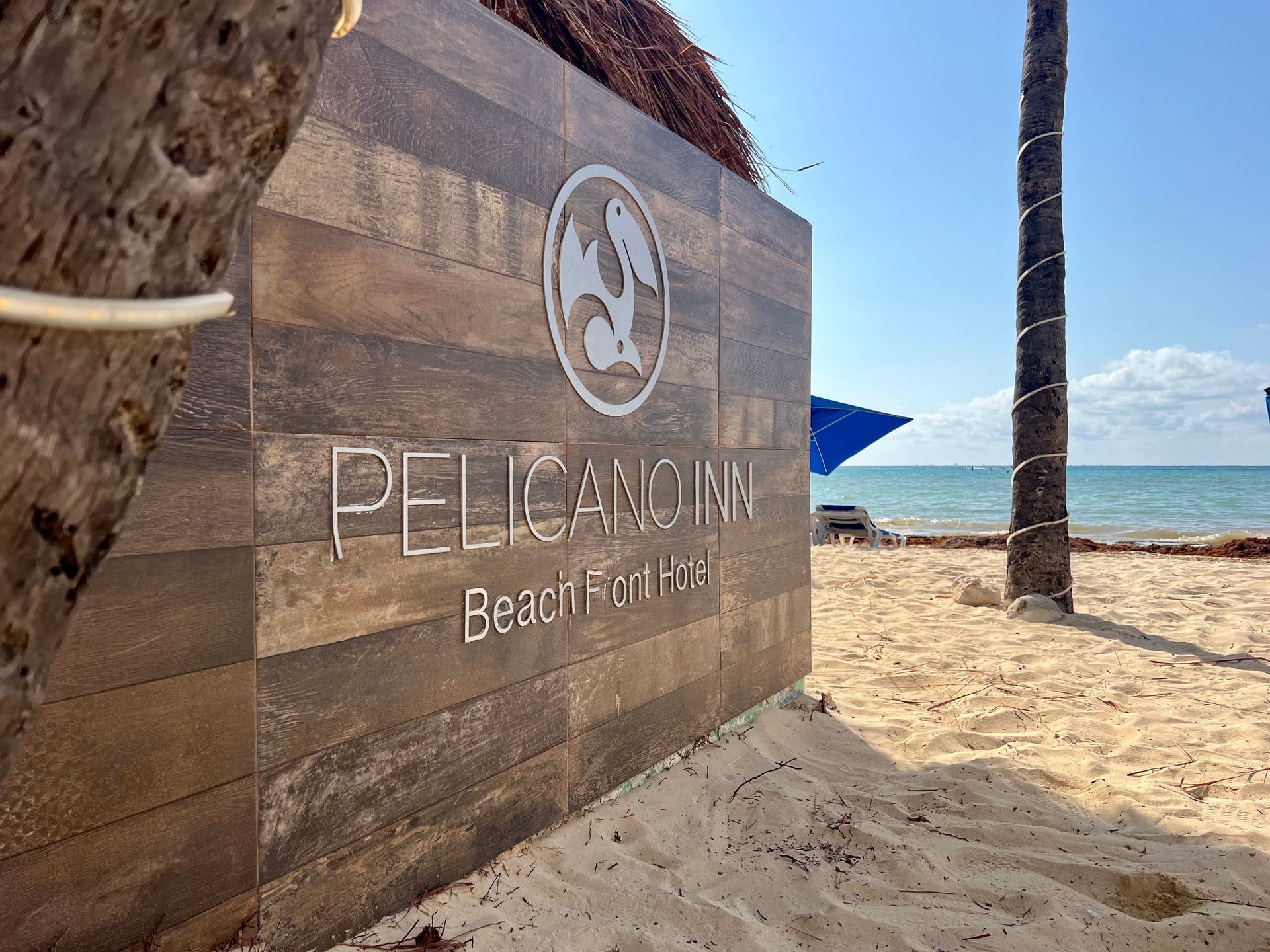 Un cartel de madera en una playa que dice Pelican Inn.