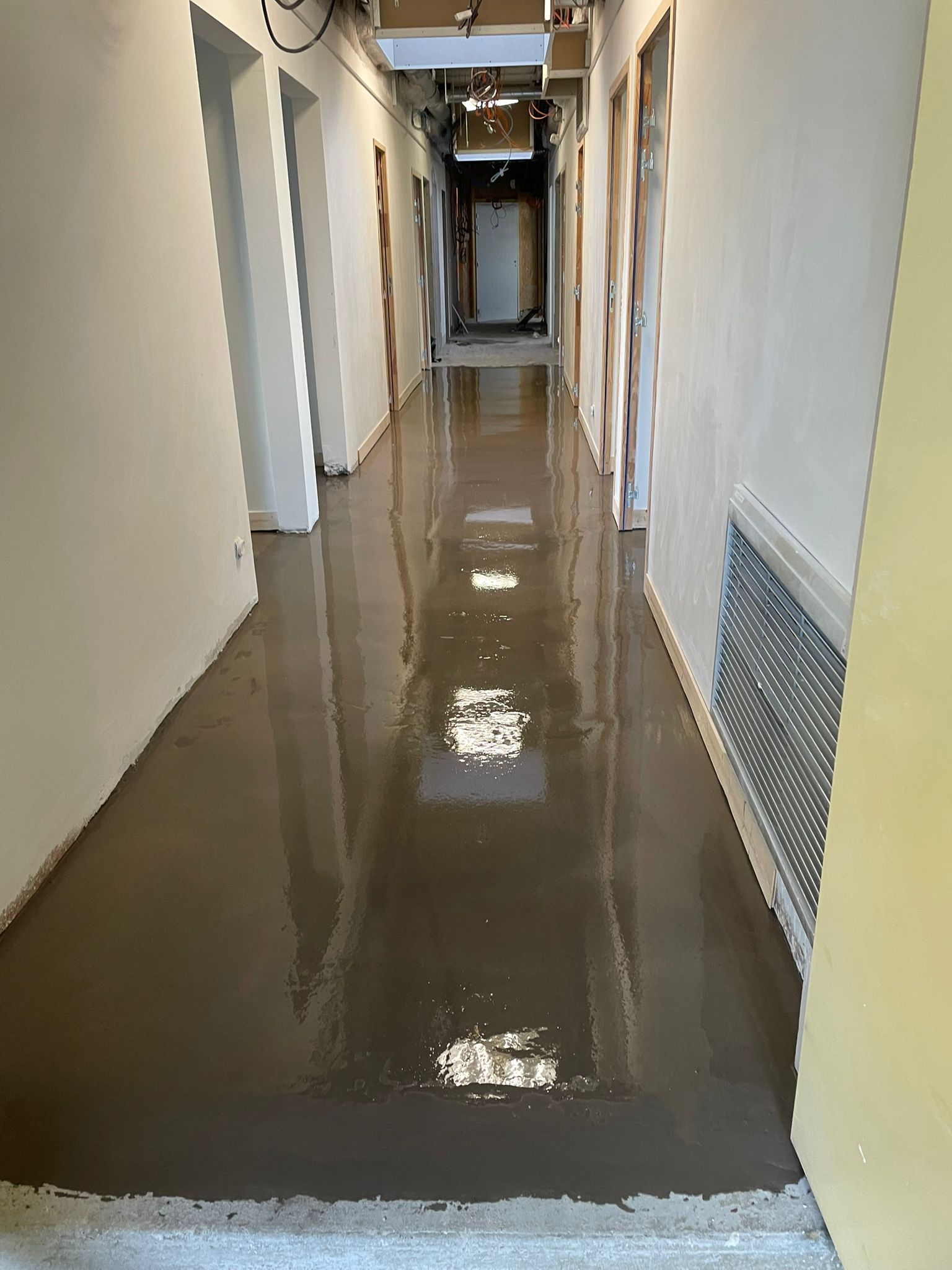 Un long couloir avec un sol en béton dans un immeuble en construction avec notre entreprise de peinture normandie.