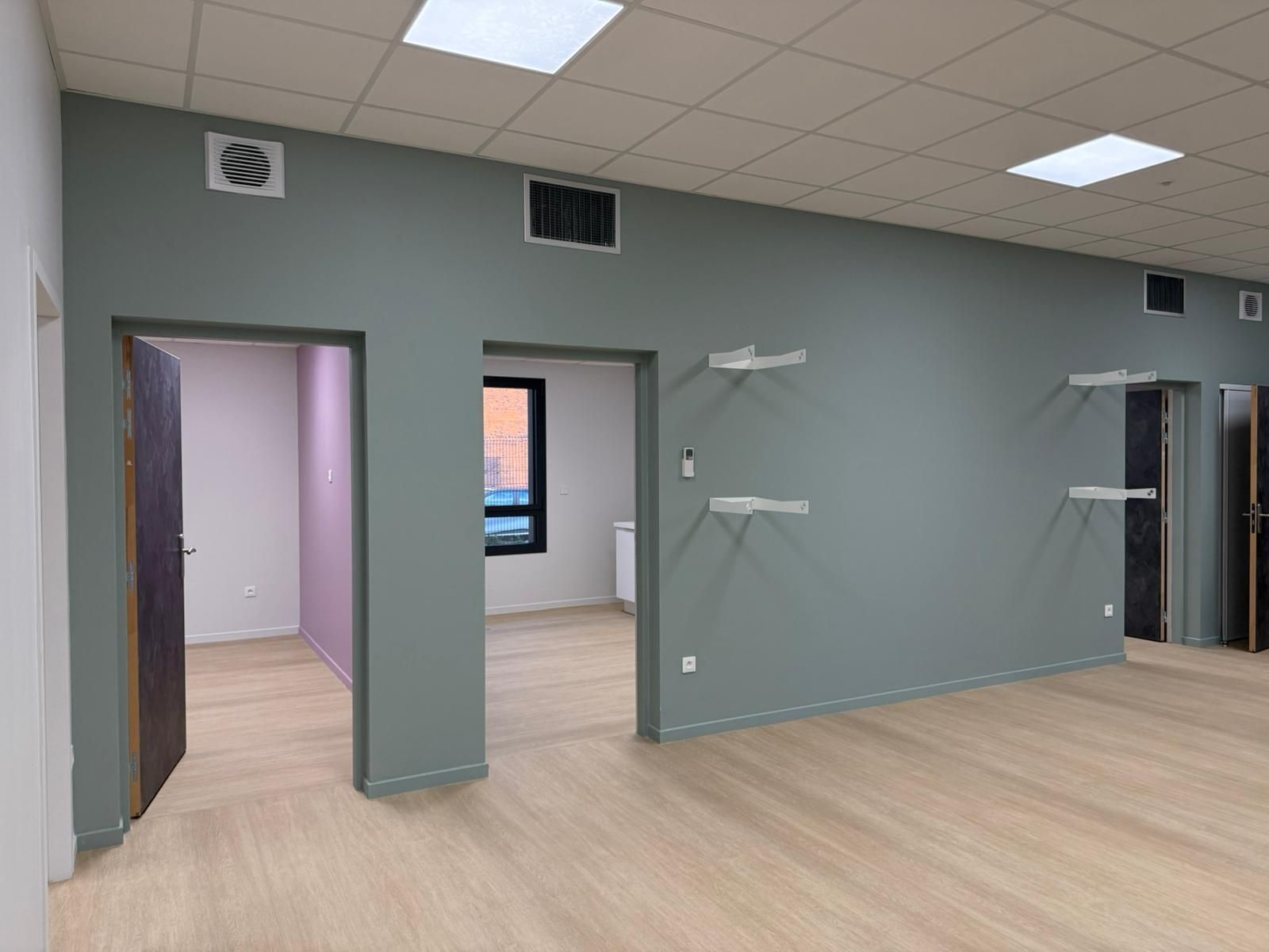 Une grande pièce vide avec un plancher en bois et des murs gris avec notre entreprise de peinture normandie.