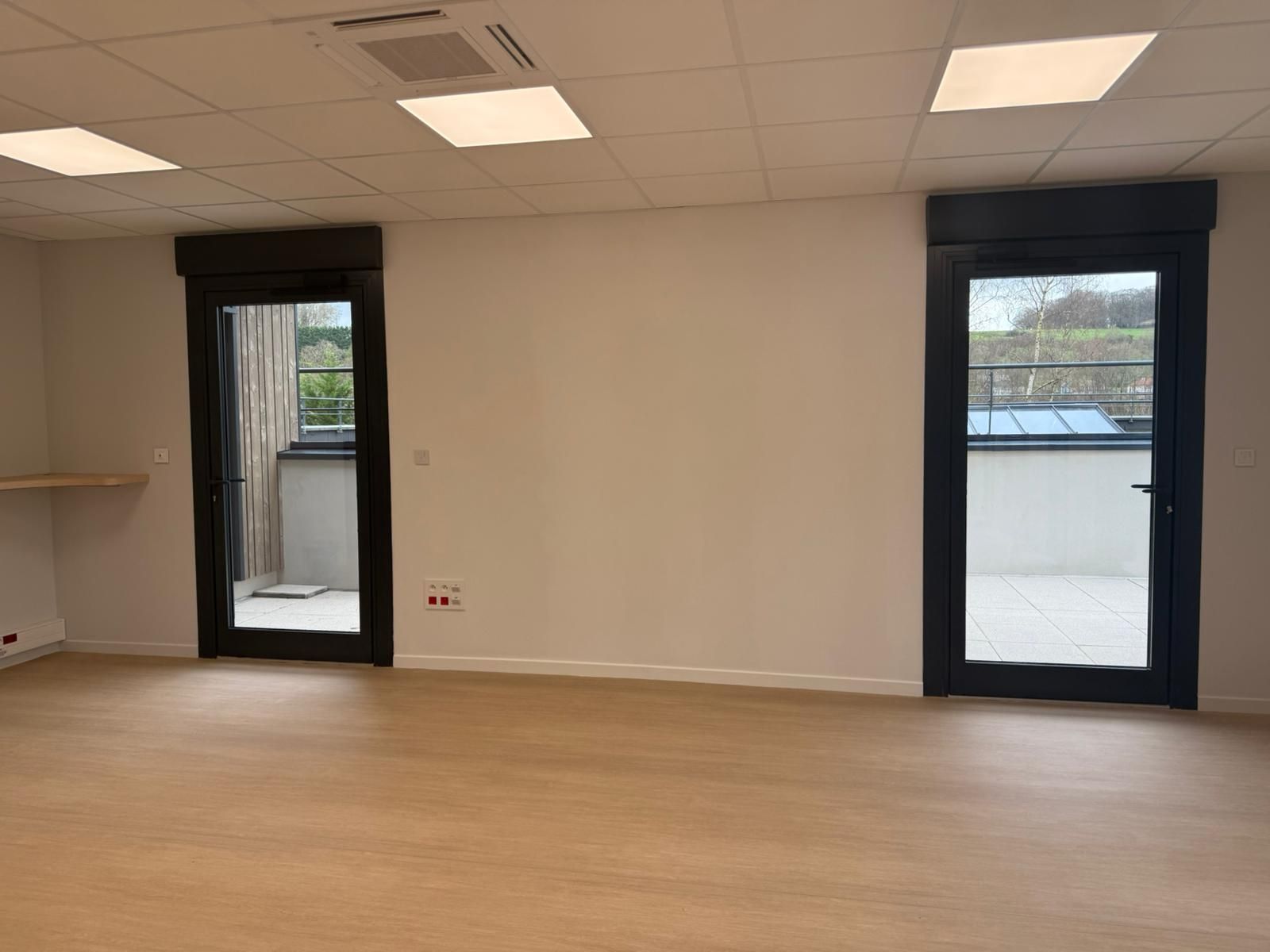 Une pièce vide avec deux portes et un balcon avec notre entreprise de peinture normandie