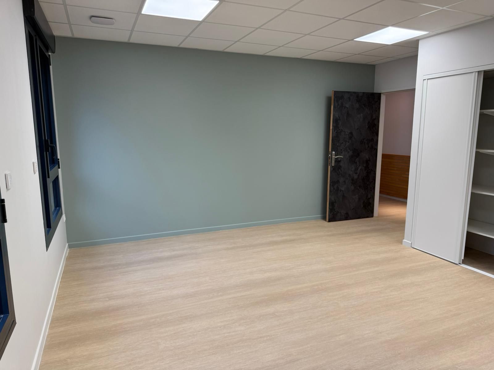 Une pièce vide avec un plancher en bois et une porte avec notre entreprise de peinture normandie.