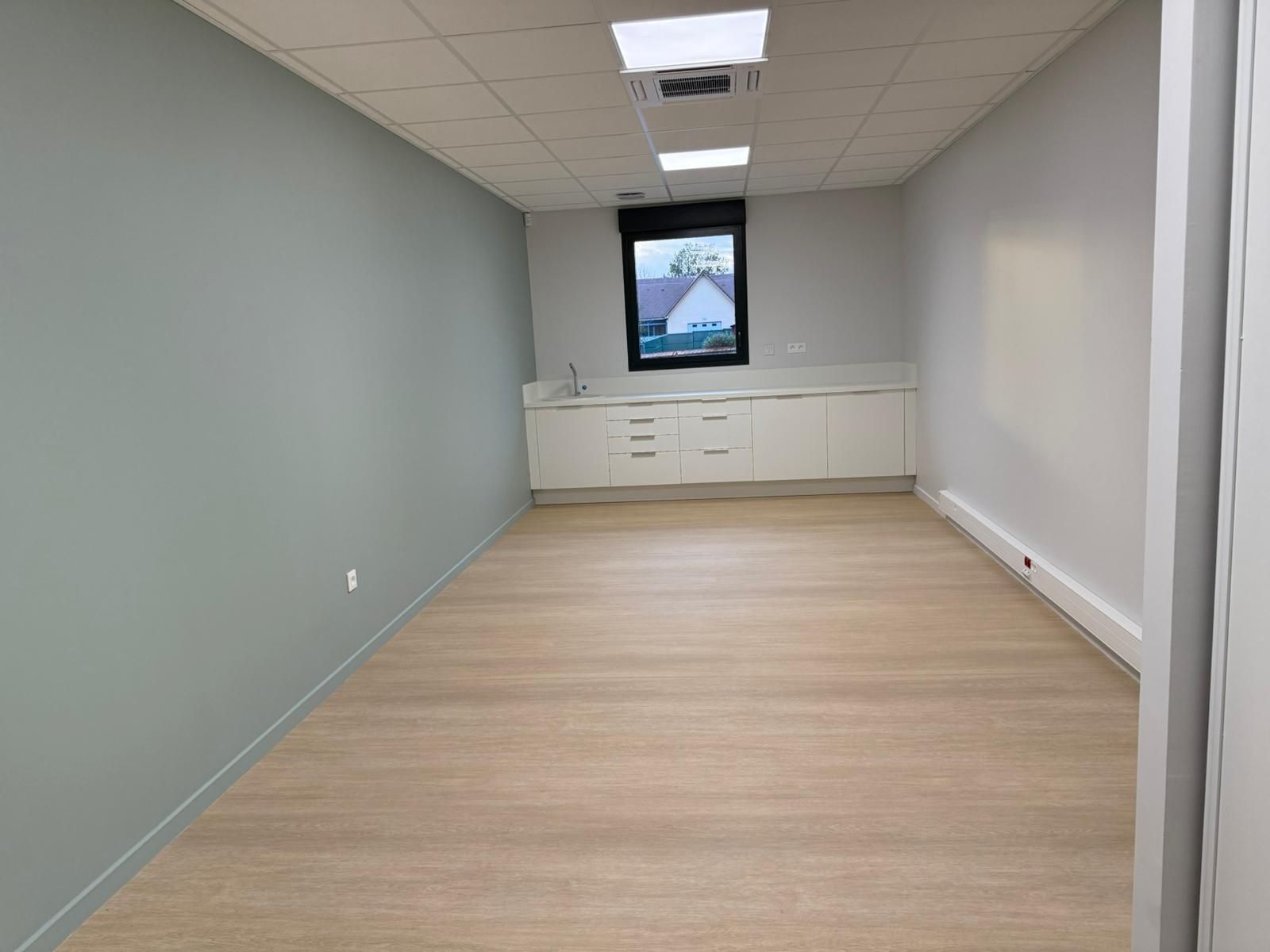 Une pièce vide avec un plancher en bois et une fenêtre avec notre entreprise de peinture normandie.