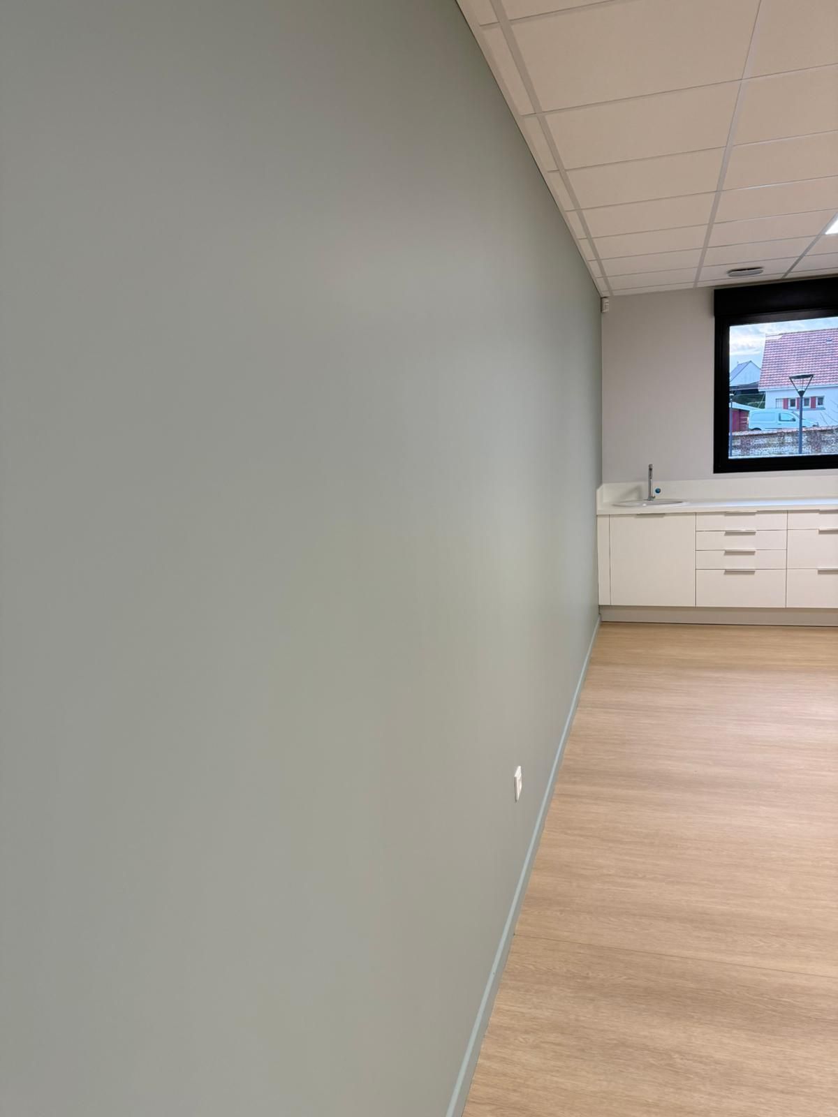 Une pièce vide avec un mur gris et un plancher en bois avec notre entreprise de peinture normandie.