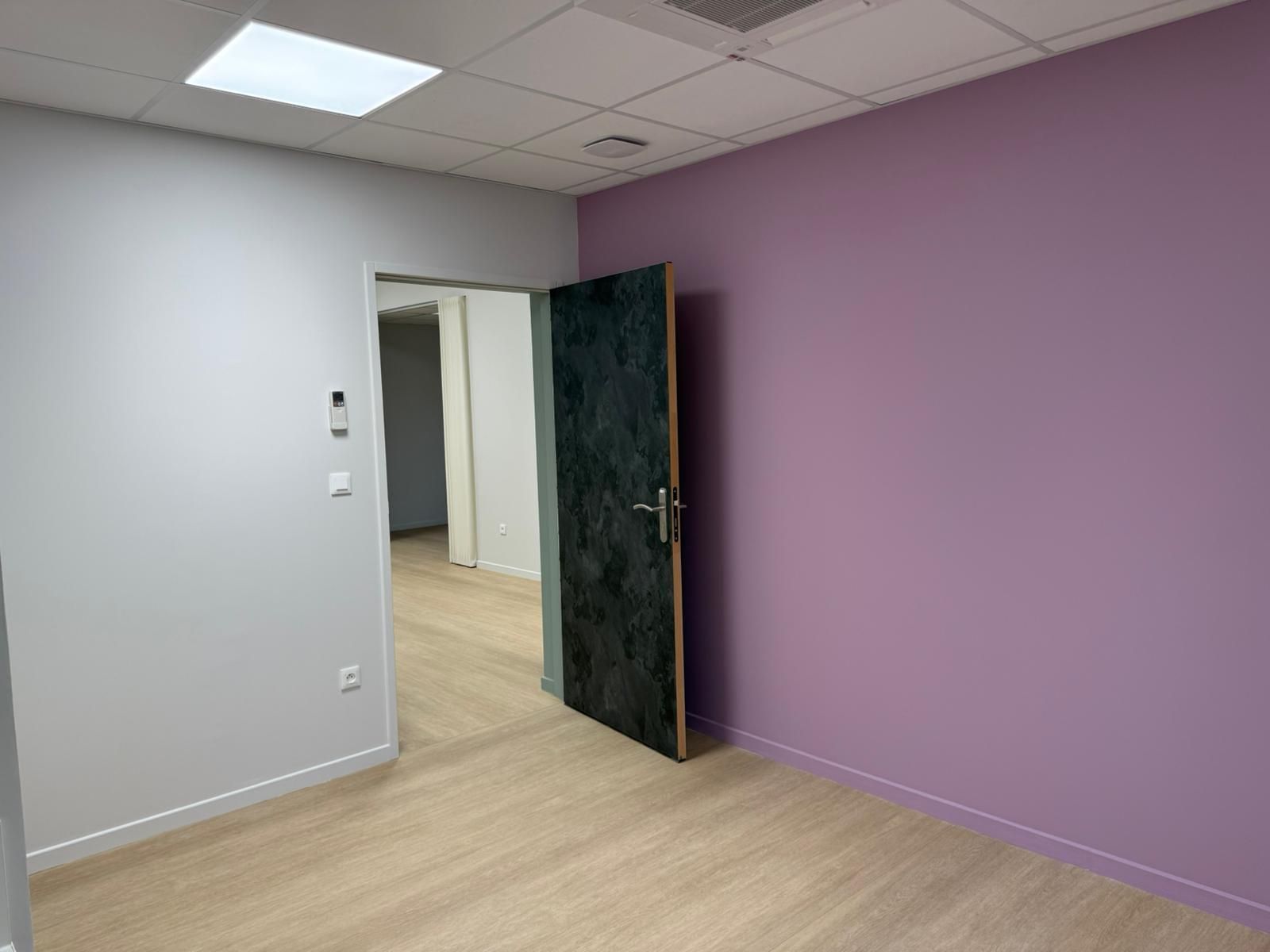 Une pièce vide avec des murs violets et une porte noire avec notre entreprise de peinture normandie.