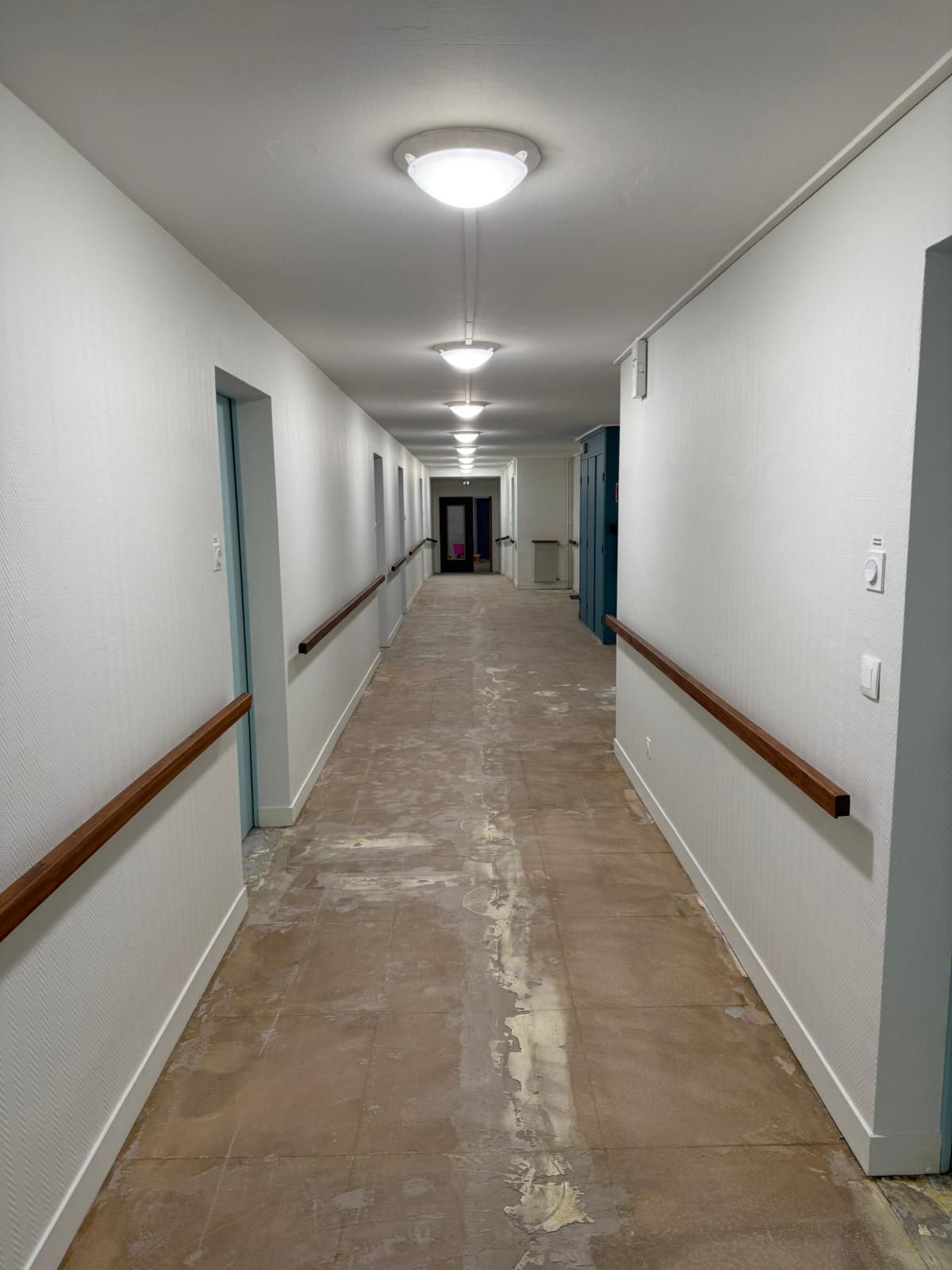 Un long couloir avec des murs blancs et des rampes en bois avec notre entreprise de peinture normandie