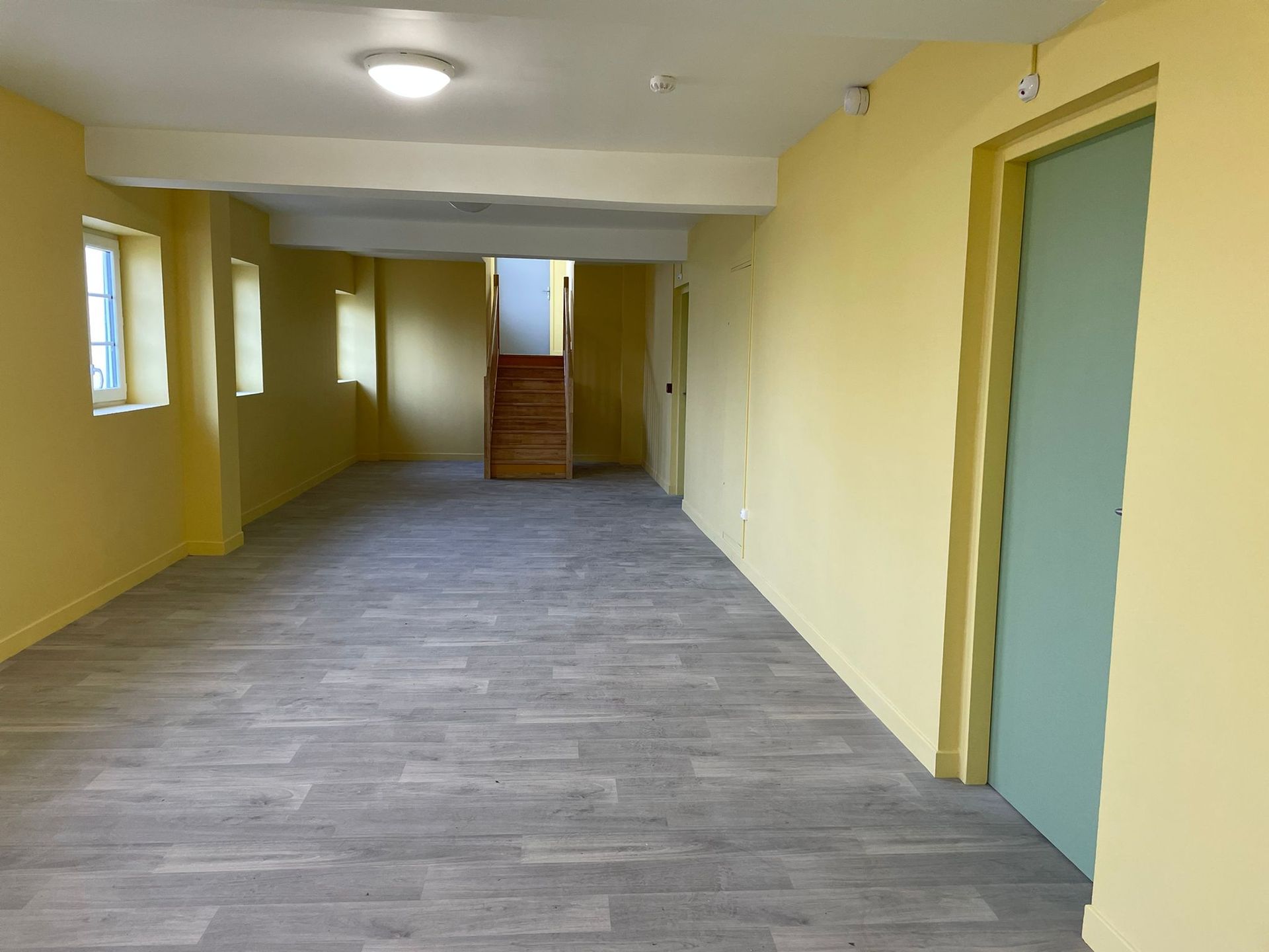 Une pièce vide avec des murs jaunes et une porte verte avec notre entreprise de peinture normandie