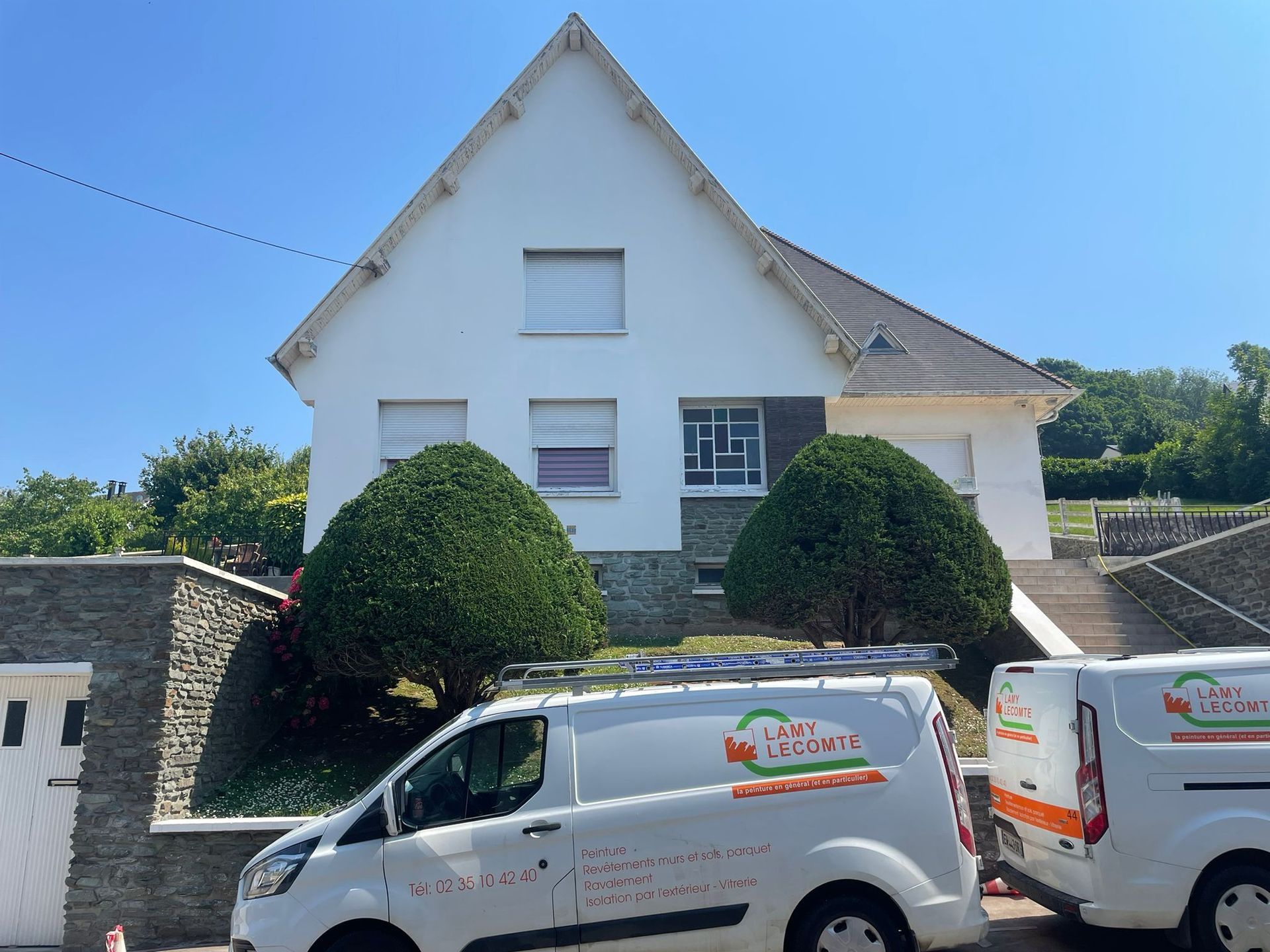 Deux camionnettes blanches sont garées devant une maison blanche avec notre entreprise de peinture normandie