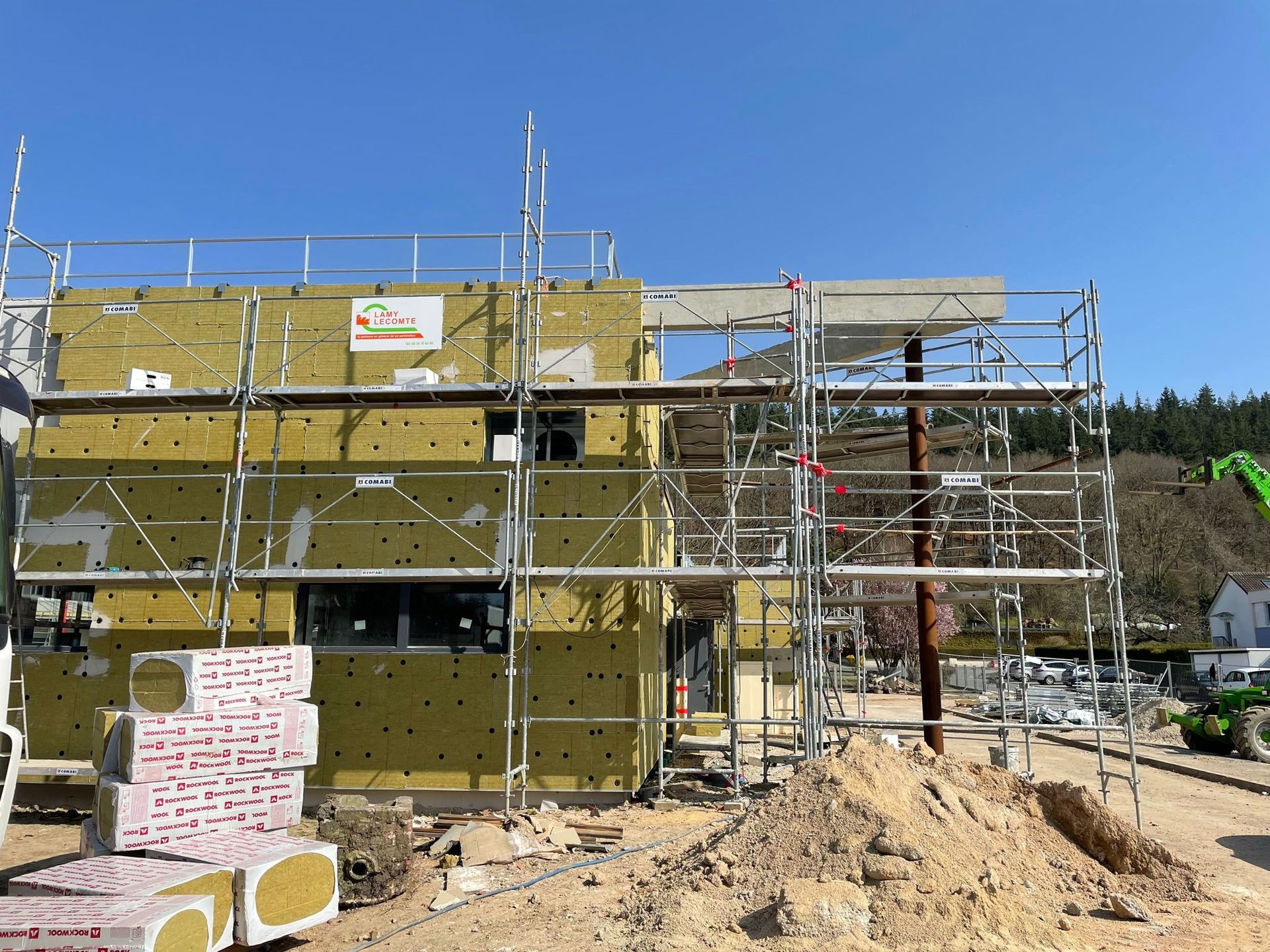 Un bâtiment est en cours de construction avec des échafaudages autour avec notre entreprise de peinture normandie.