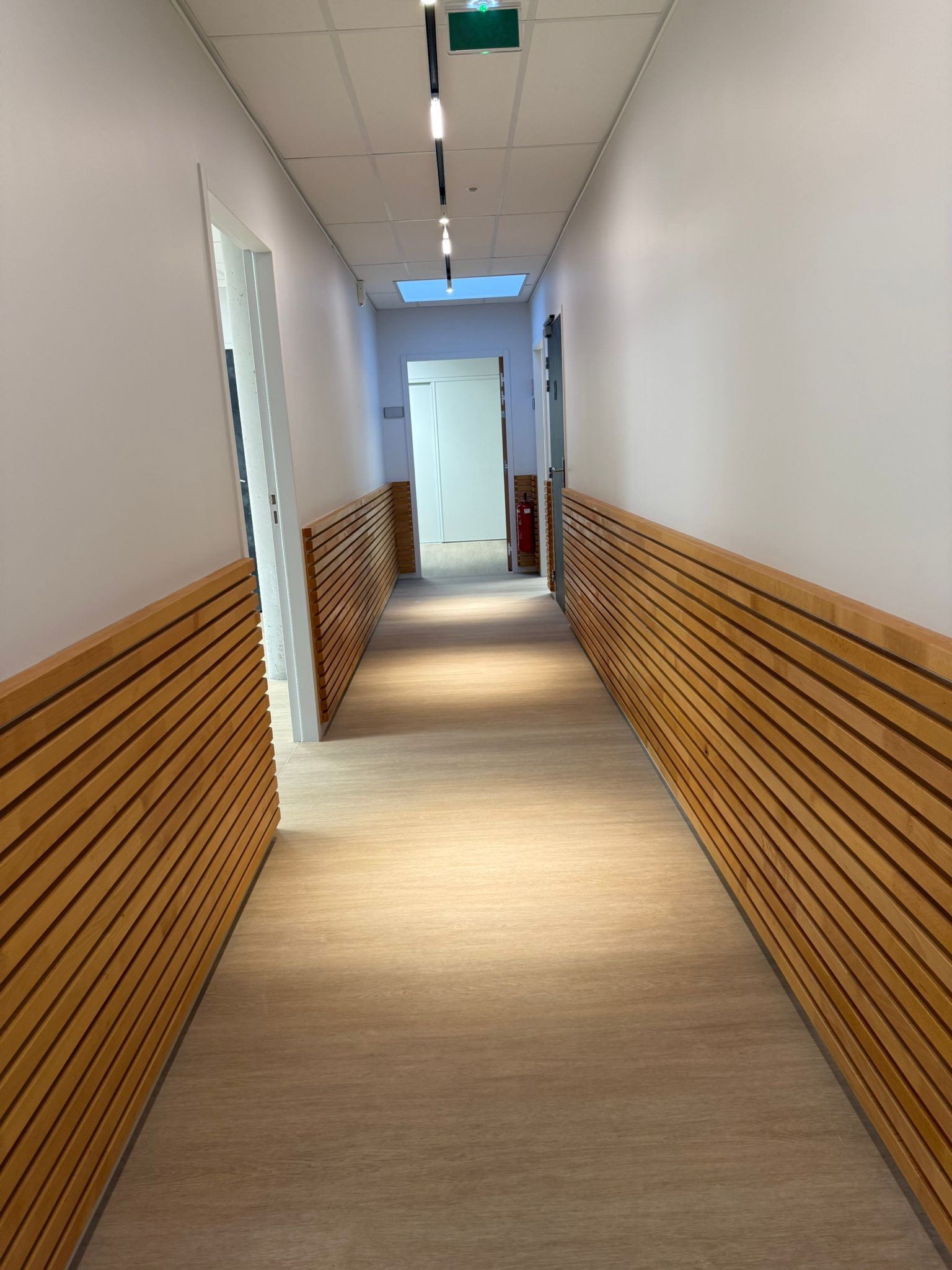 Un long couloir avec des murs en bois et une lumière verte au plafond avec notre entreprise de peinture normandie