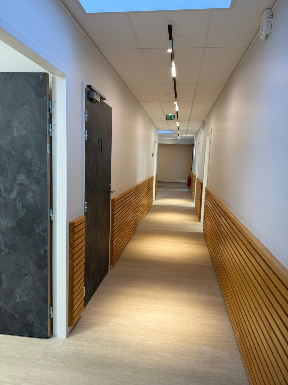 Un long couloir avec des murs en bois et une porte noire avec notre entreprise de peinture normandie