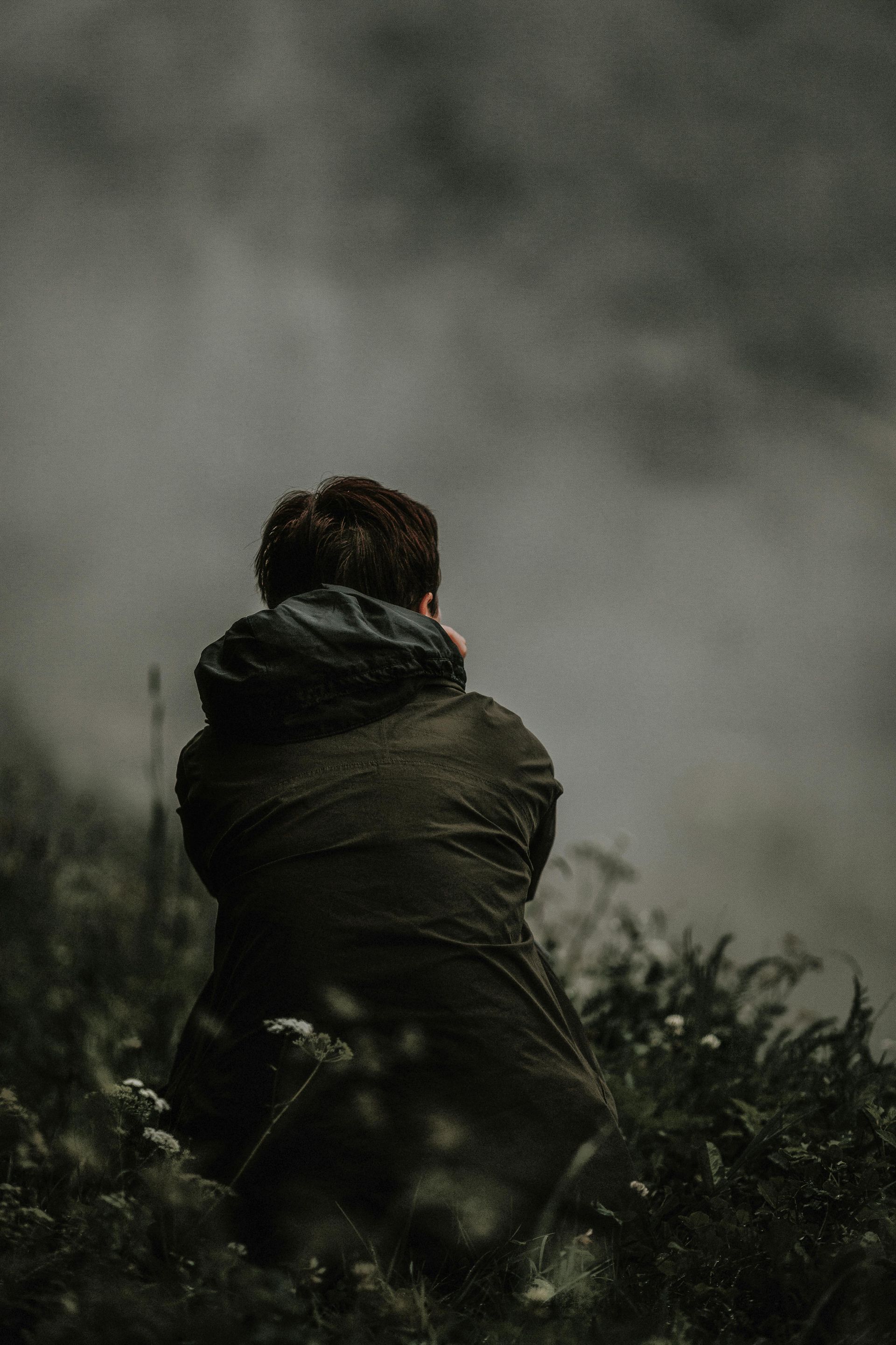 Un homme est agenouillé dans un champ et regarde le ciel.