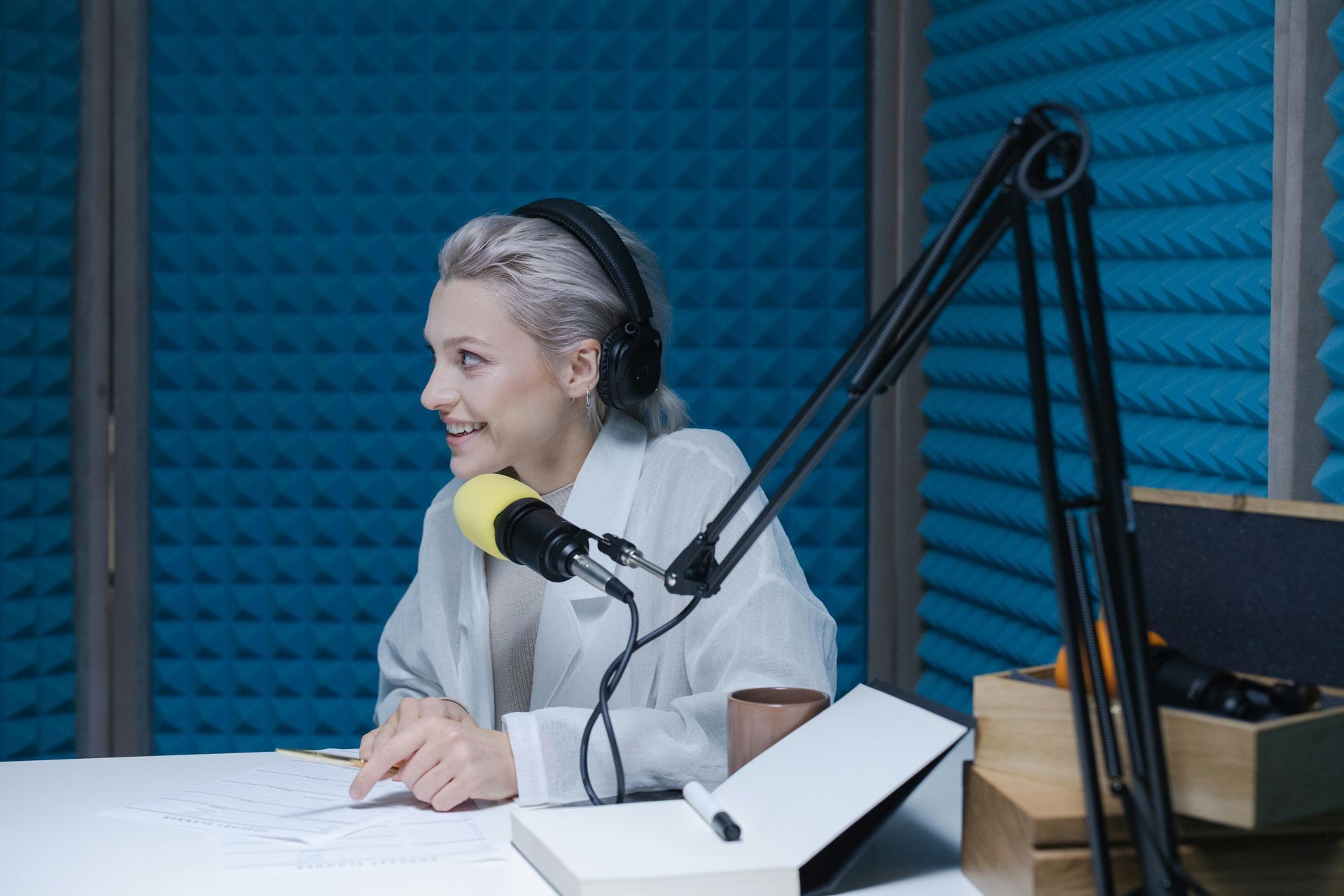 Une femme est assise à une table devant un microphone dans un studio d'enregistrement.