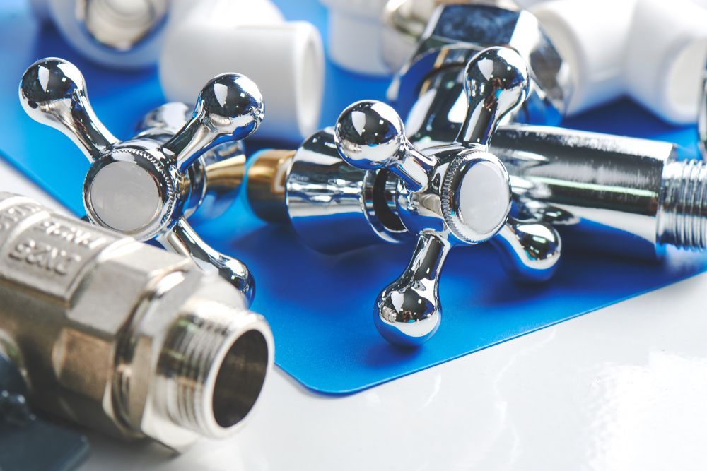 Close-up of shiny chrome plumbing fixtures and white plastic fittings on a blue surface.
