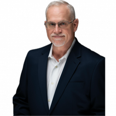 Man with gray hair and glasses in a navy blue suit and white shirt, smiling.