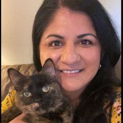 Woman holding a tortoiseshell cat, both smiling at the camera.