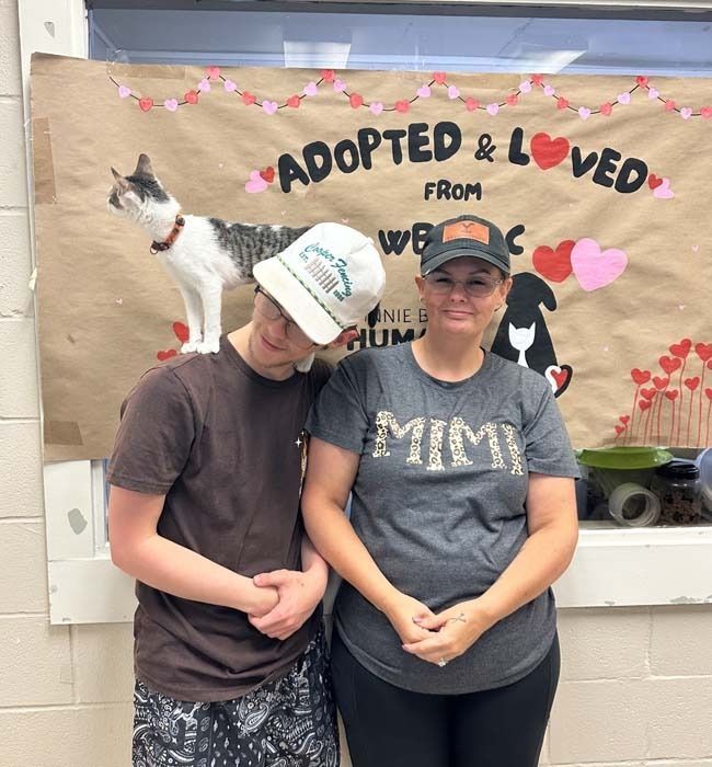 Two people pose in front of a banner that says