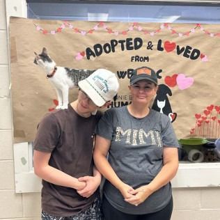 Two people and a cat pose under a