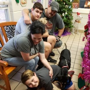 Family with a puppy in a decorated room, one person petting the dog, others watching.