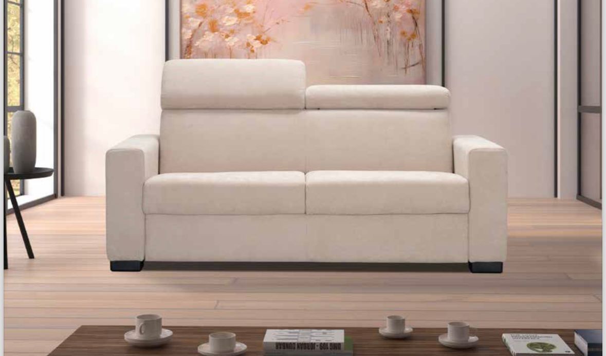 Un divano moderno color crema con poggiatesta regolabile, posizionato in una stanza luminosa e minimalista con un tavolino da caffè.