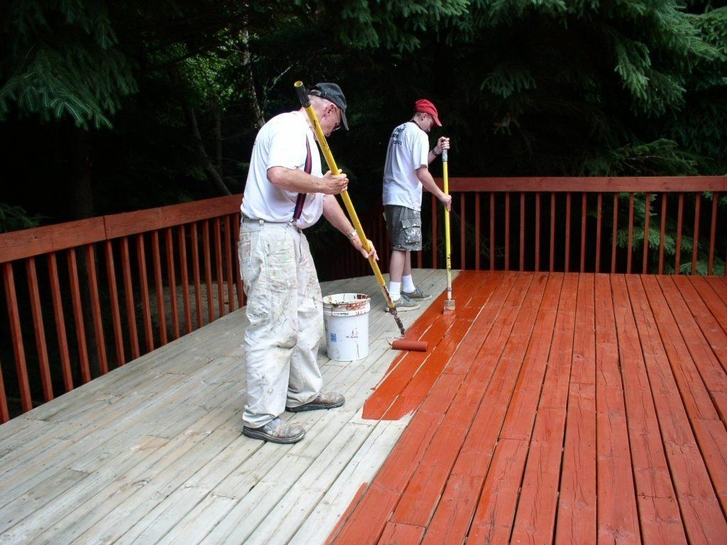 Two painters applying deck coating on an outdoor deck in Madison, WI