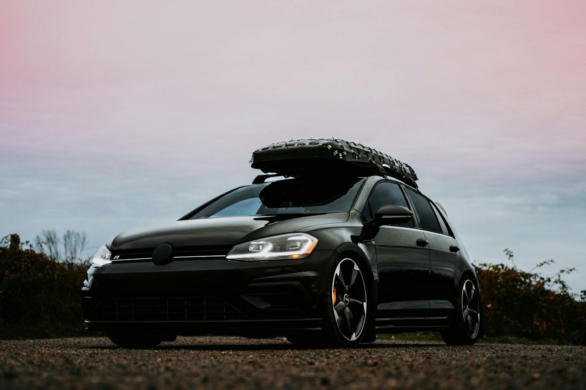 A wooden trailer is parked in a field with trees in the background.