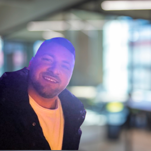 A man with a beard is smiling in a blurry photo