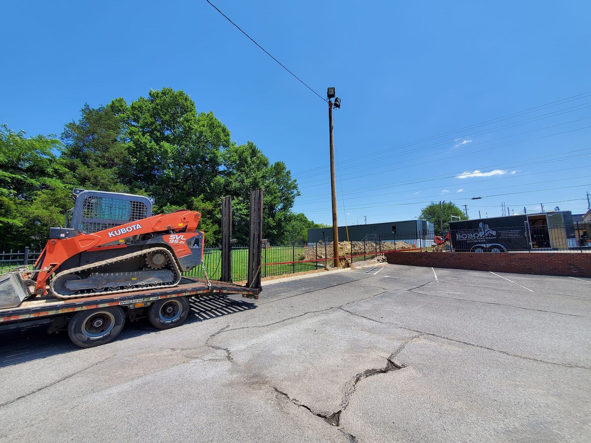 A bulldozer is sitting on a trailer in a parking lot.