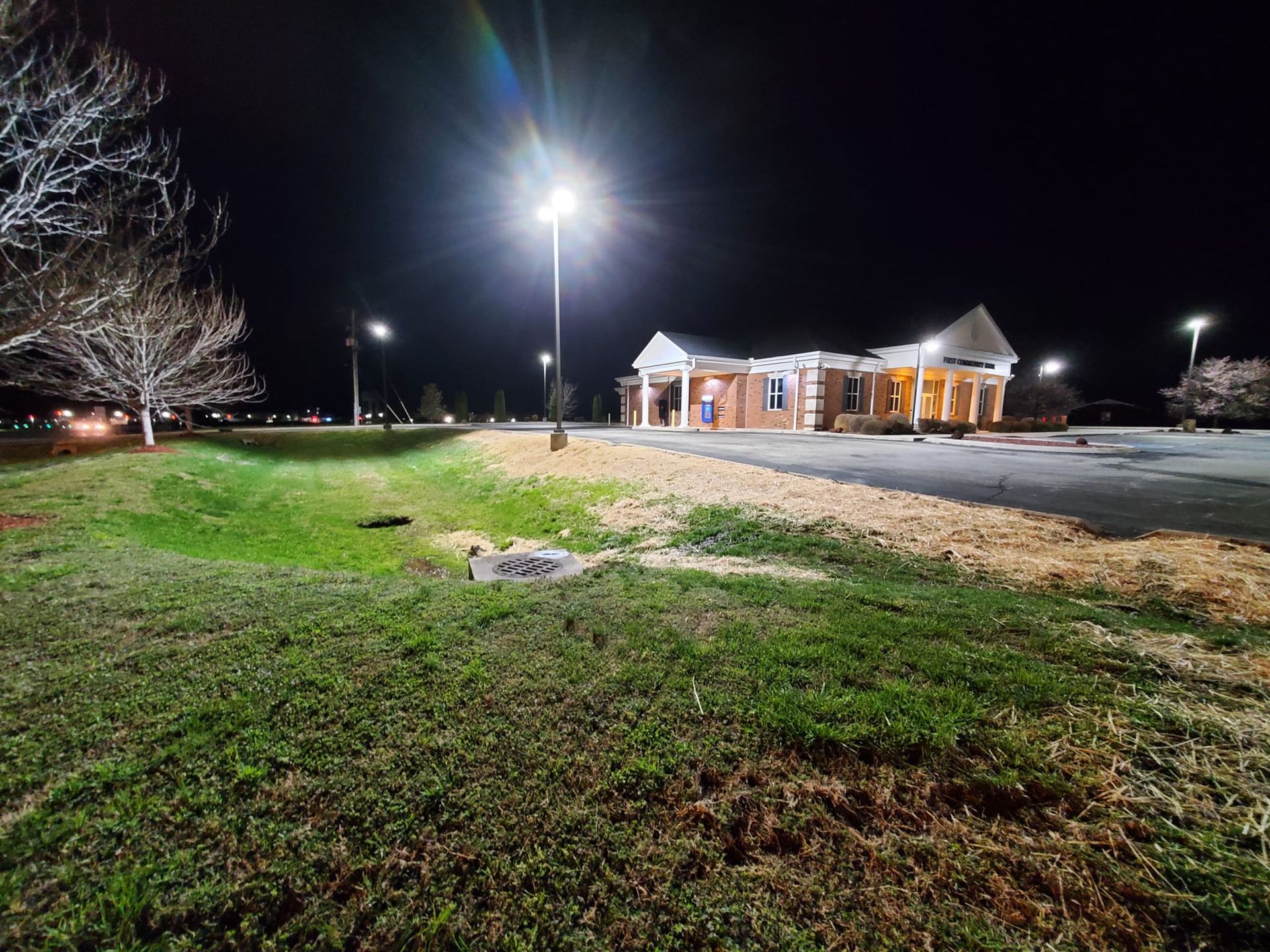 A large building is lit up at night in a parking lot.