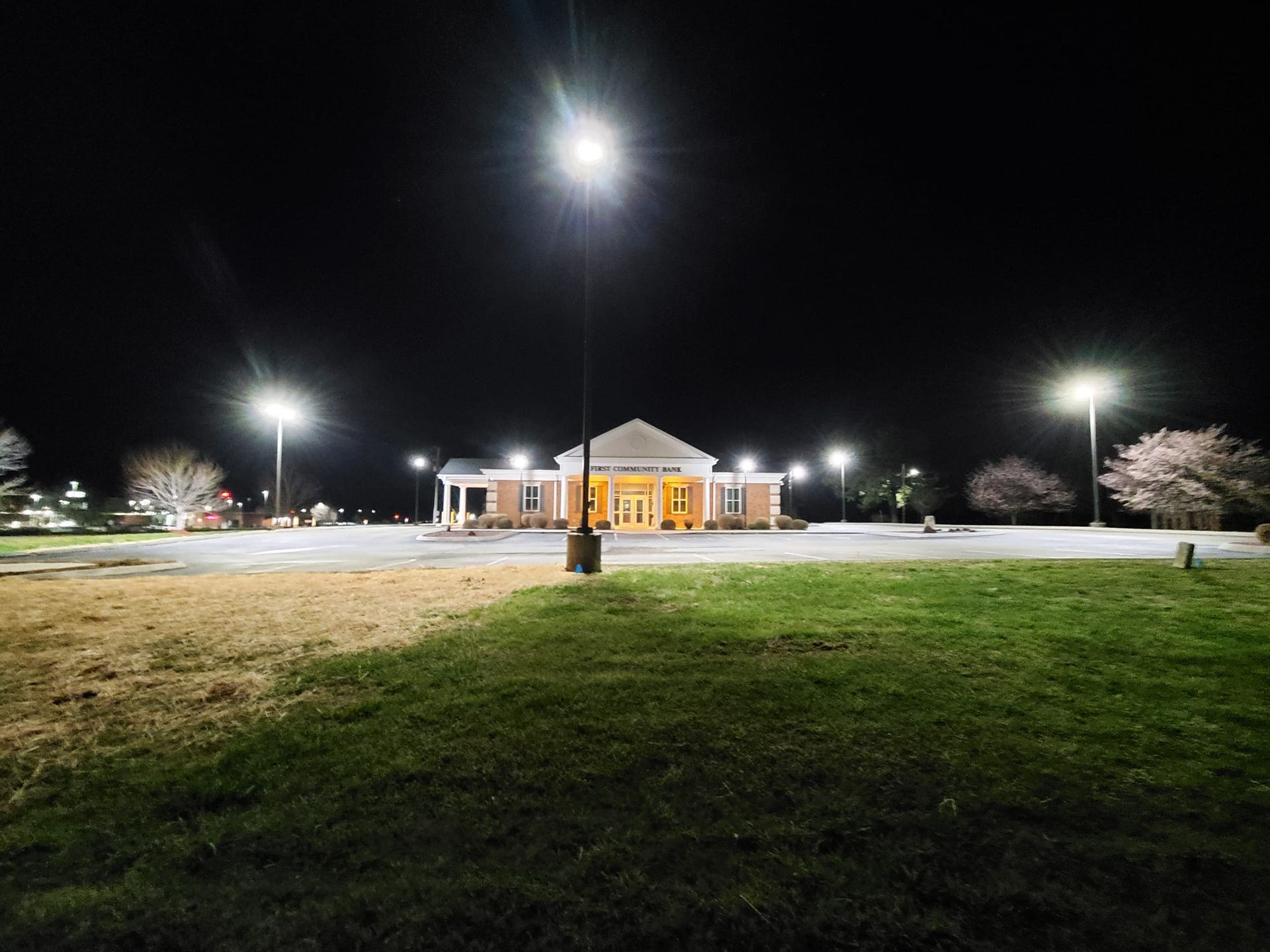 A large building is lit up at night in a park.