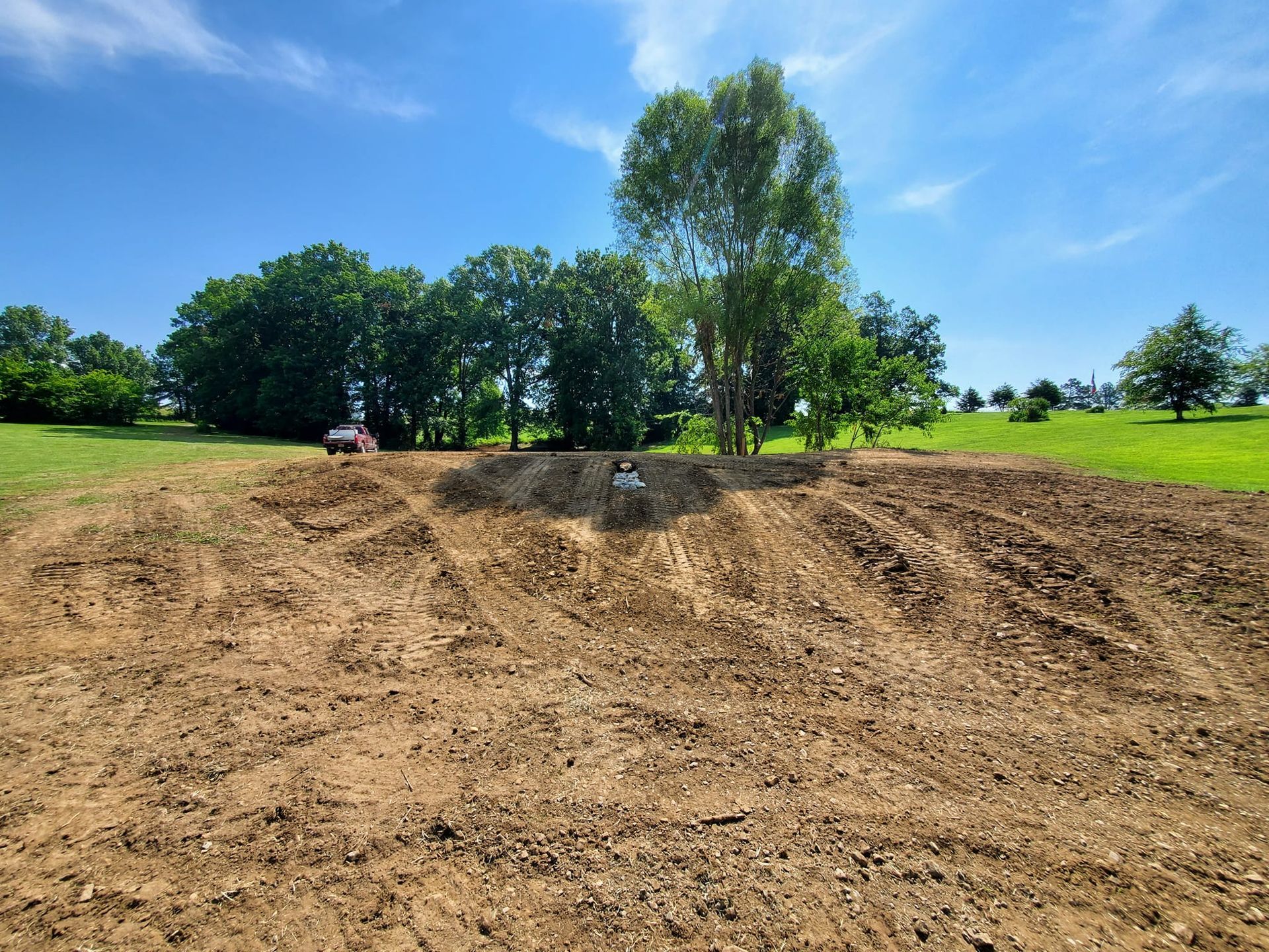 A dirt field with trees in the background on a sunny day