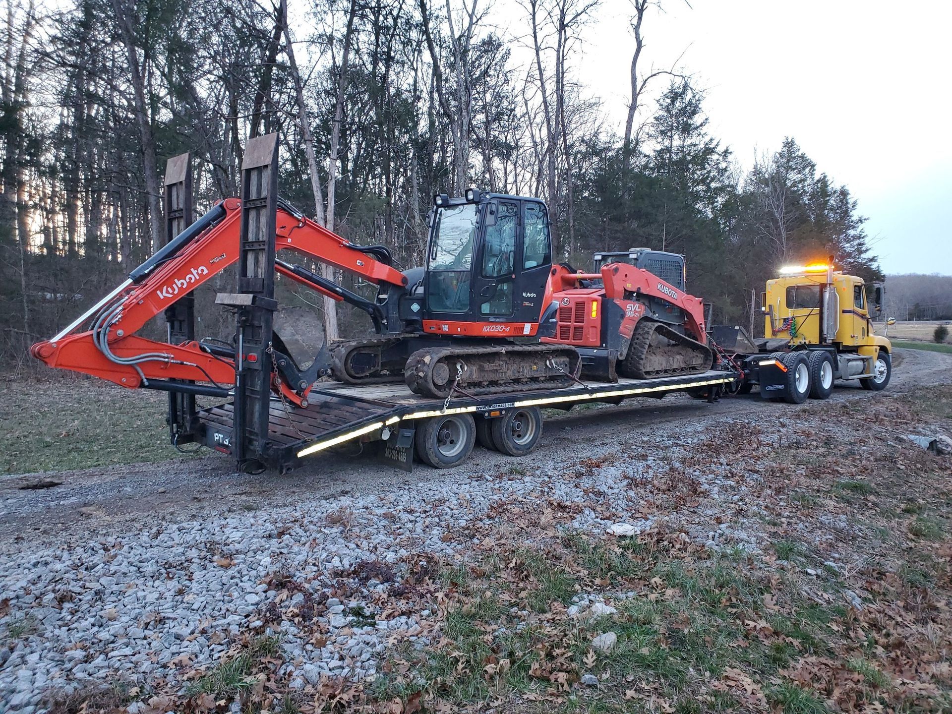 A truck is carrying a large excavator on a trailer.