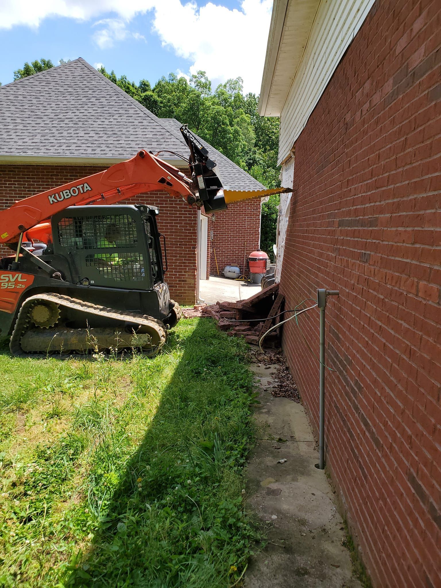 A bulldozer is parked in front of a brick house.