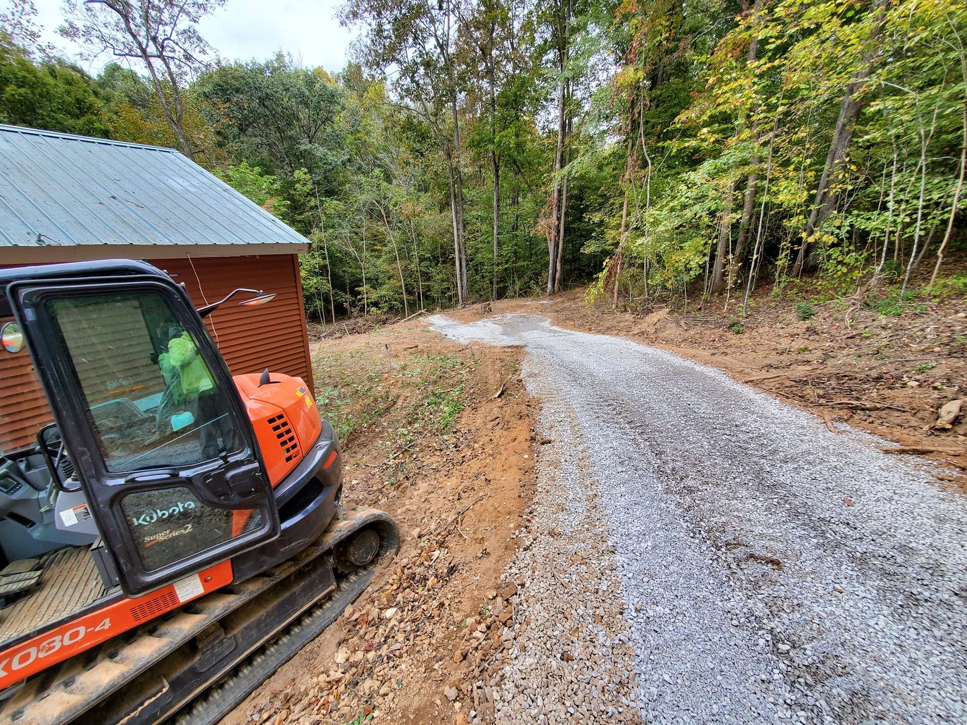 A small excavator is parked on the side of a dirt road.