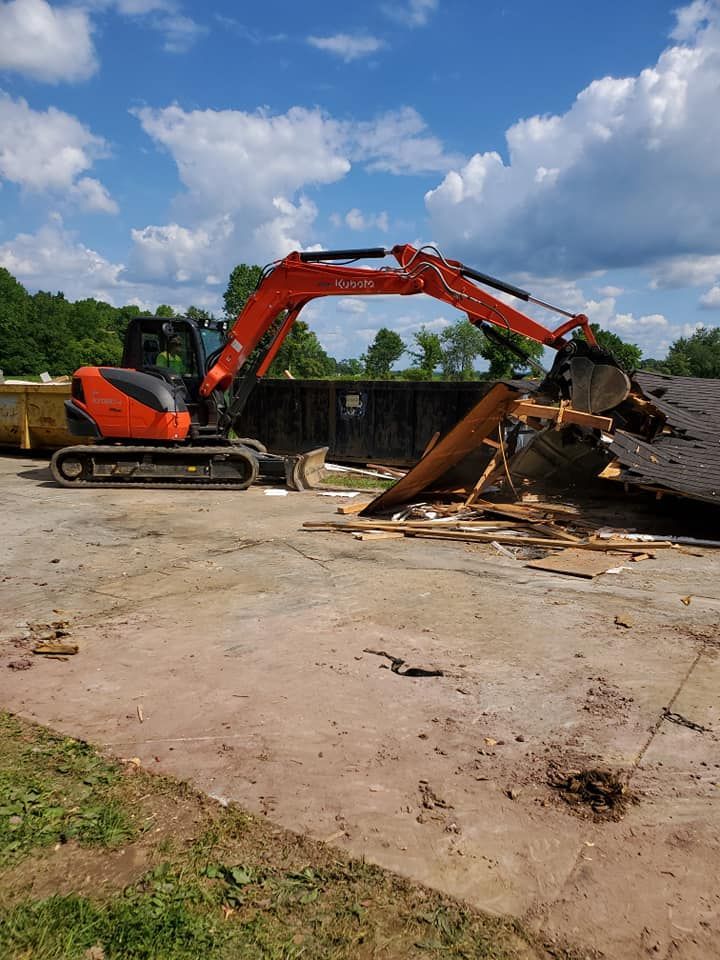 An excavator is demolishing a building in a parking lot.