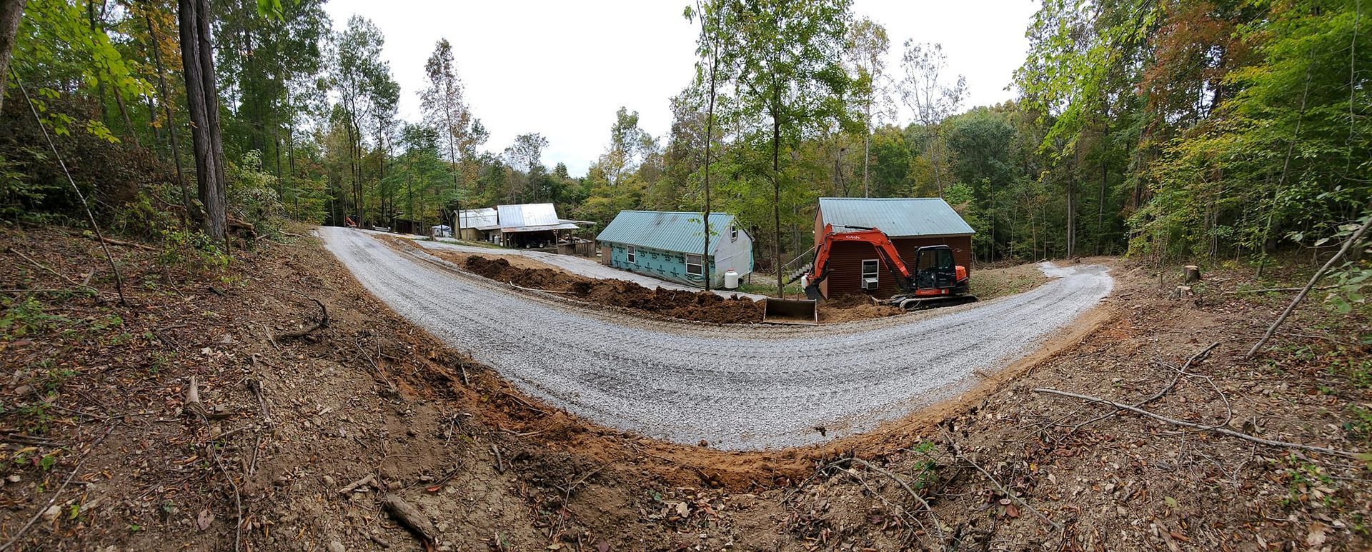 A dirt road leading to a house in the woods.