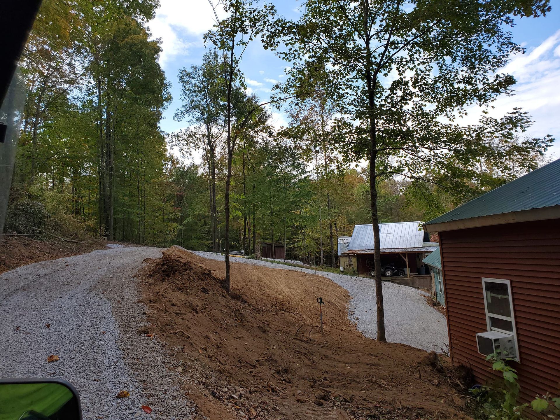 A dirt road leading to a house in the woods.