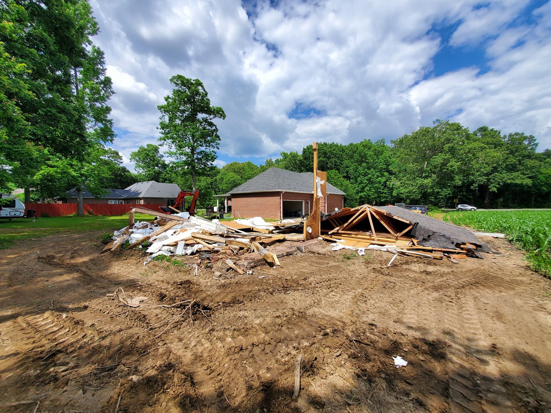 A house is being demolished in the middle of a dirt field.