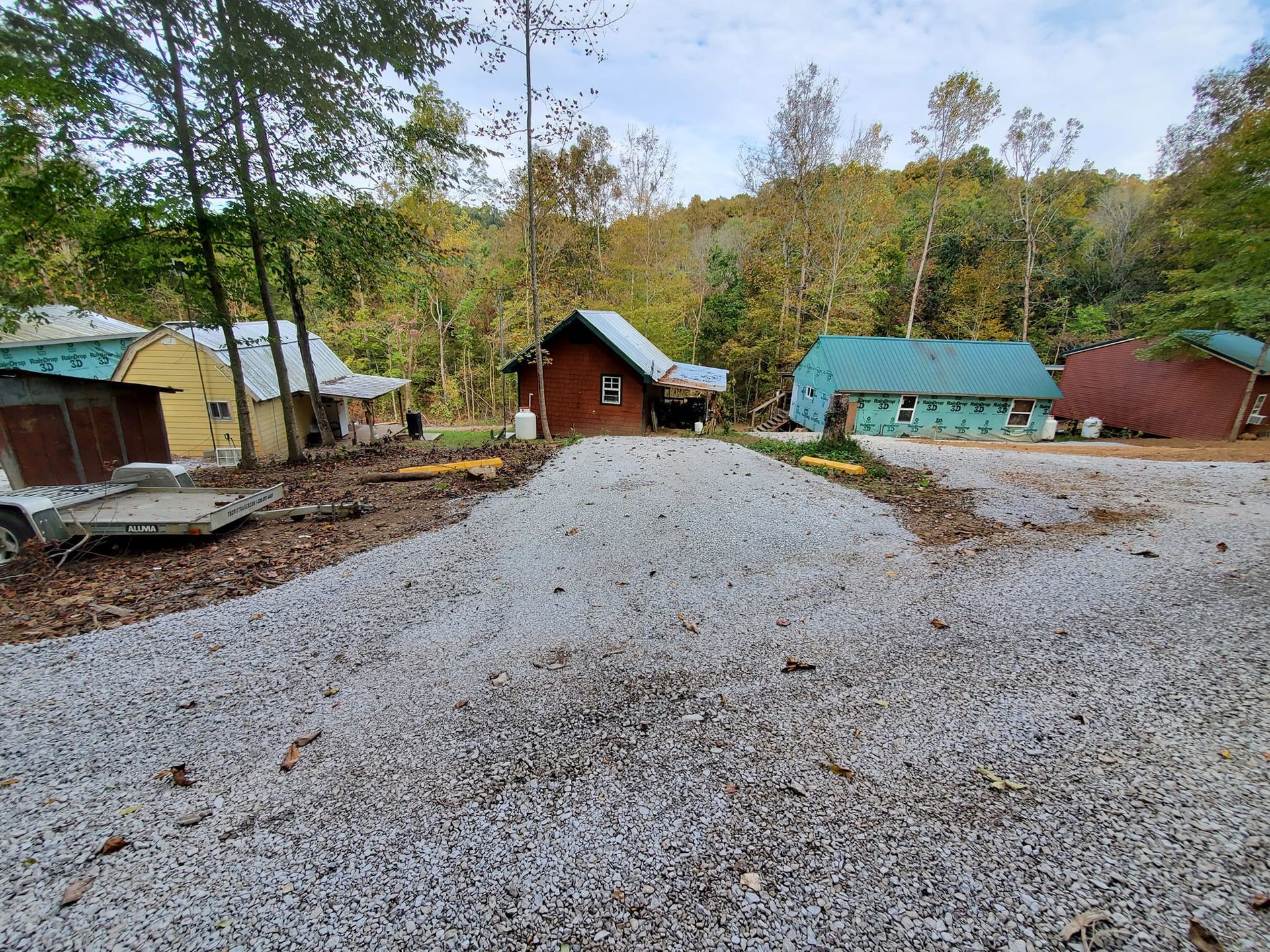 A gravel road leading to a house in the woods.