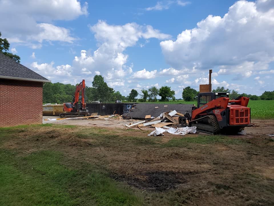 A bulldozer is sitting in a field next to a brick building.