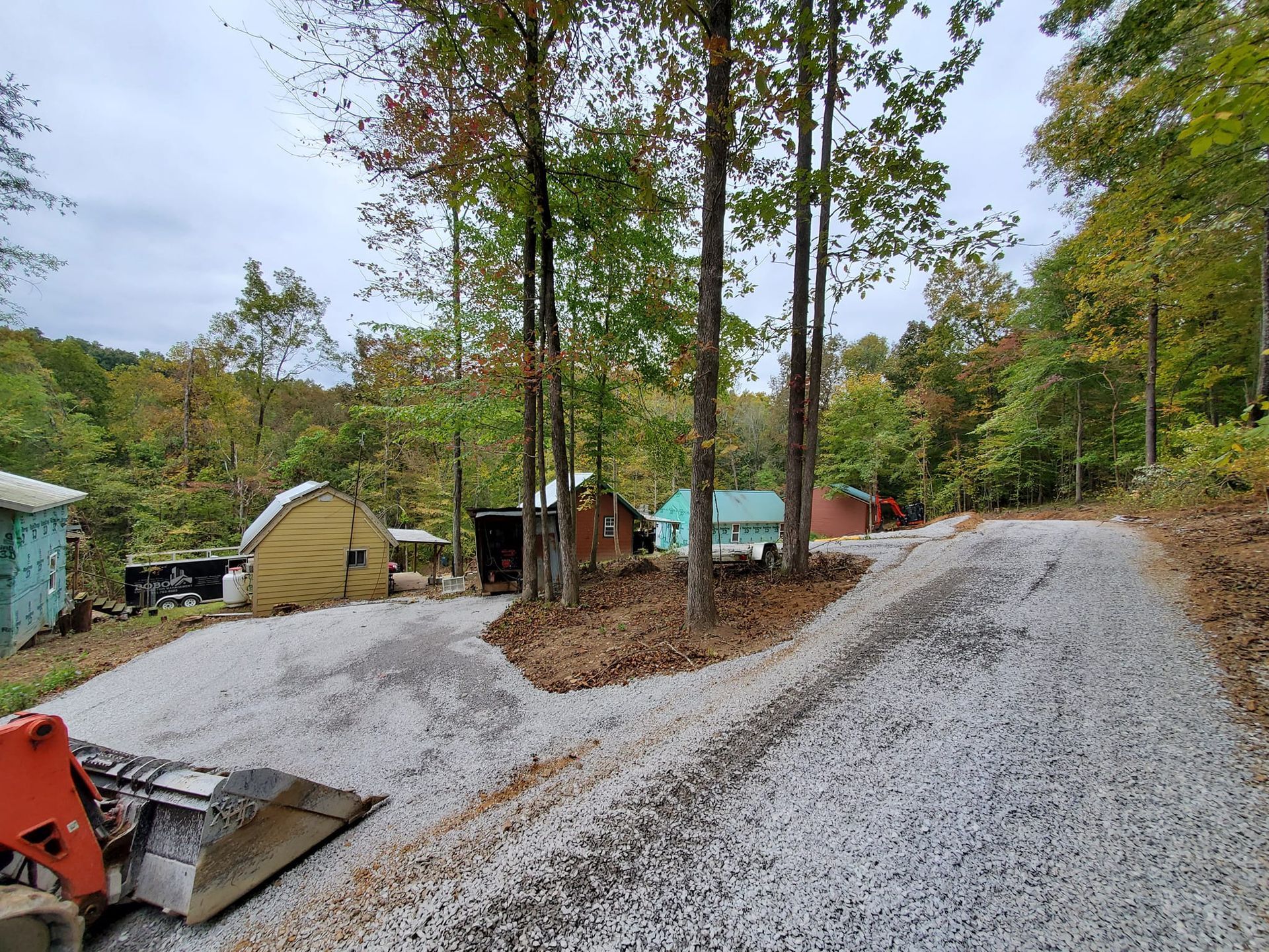 A gravel driveway leading to a house in the woods.