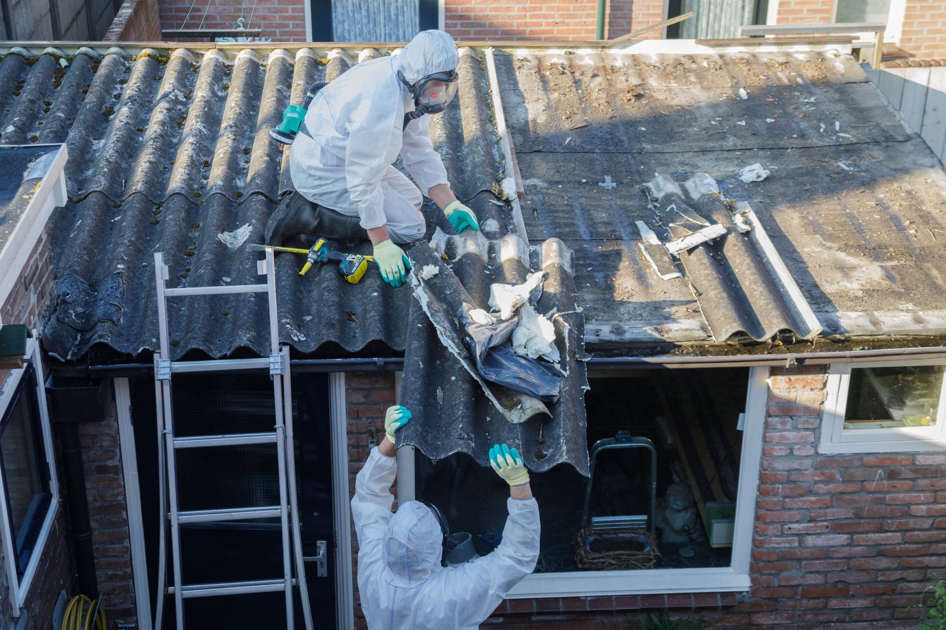 Man in protective suit removes asbestos roofing. Man in protective suit removes asbestos roofing.