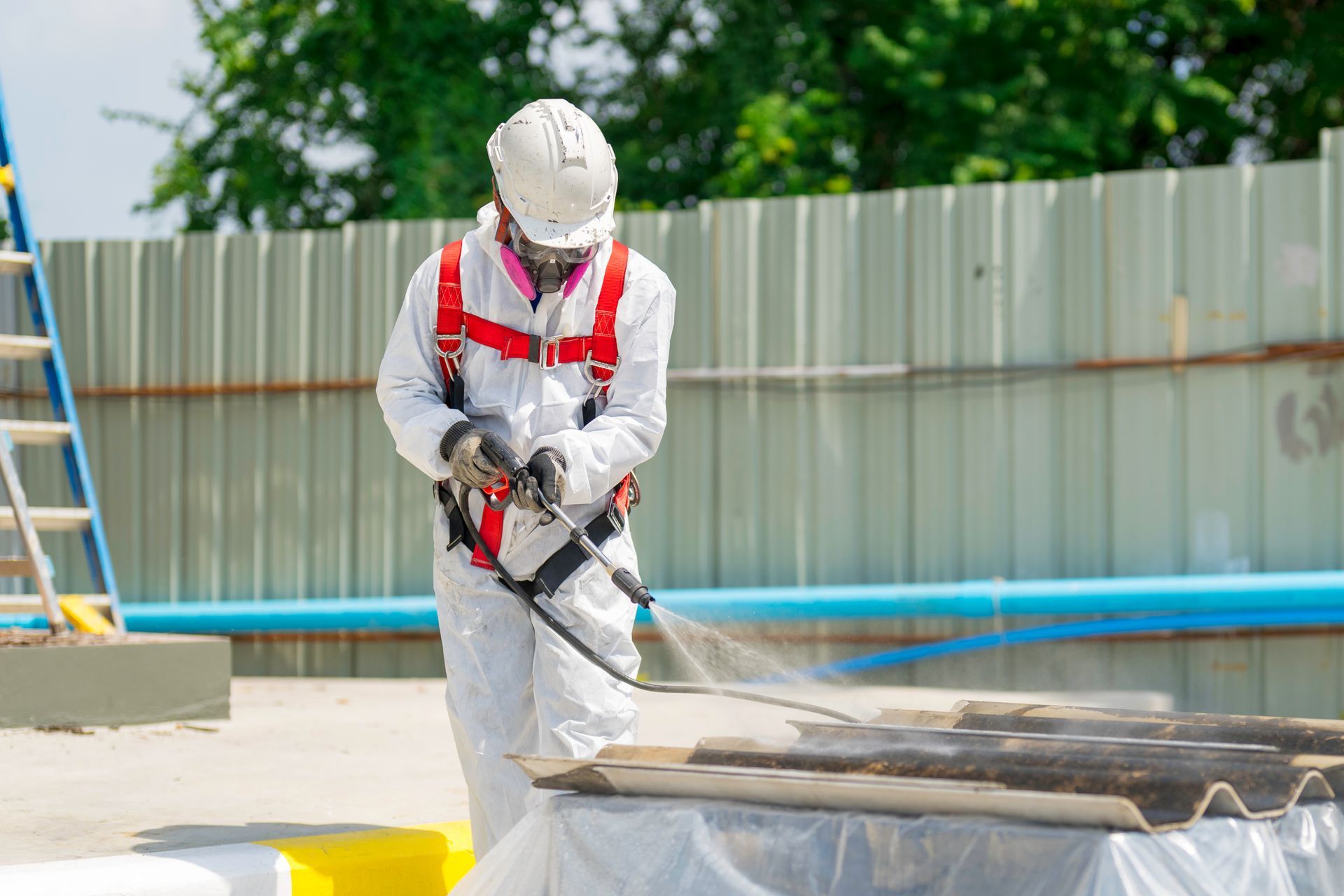 Worker wearing full-body protective clothing while working with the asbestos roof.