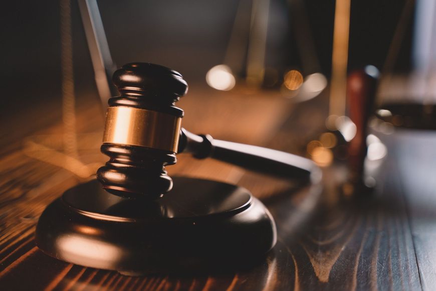 Wooden gavel and sound block on a dark wooden table, blurred background.