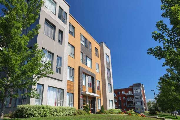 A large apartment building with a lot of windows and trees in front of it.