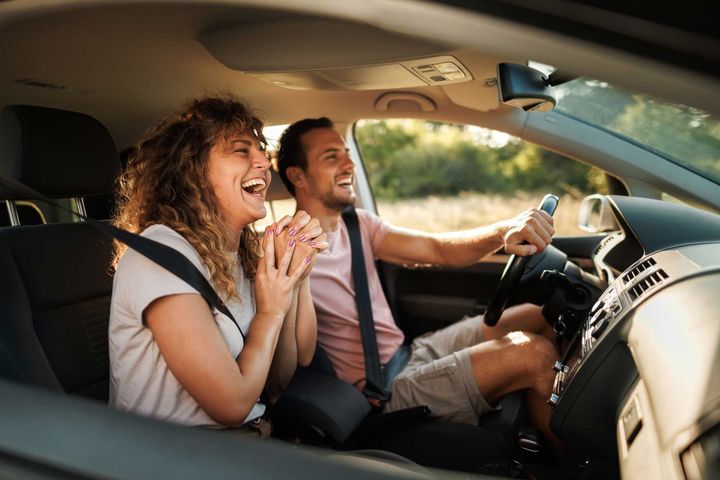 A man and a woman are laughing in a car.