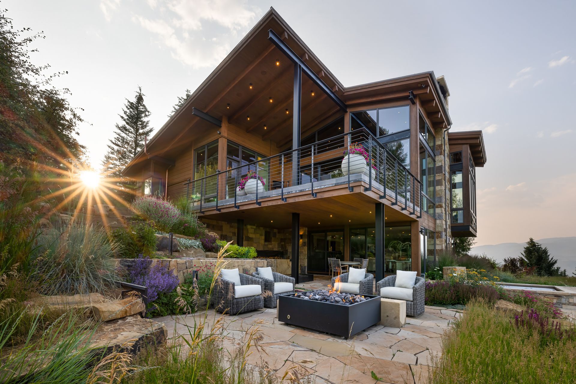 A modern house with a large deck in the middle of a field.